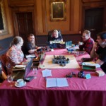 group of 6 people sitting around a D&D table in a castle room