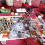messy table full of d&D maps and minis