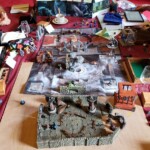 messy table full of d&D maps and minis