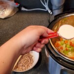 2 tablespoons of flour being poured into instapot over veggies