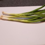 whole green onions on a cutting board