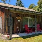 Front of a Misty forest mini cabin with two red chairs on the porch
